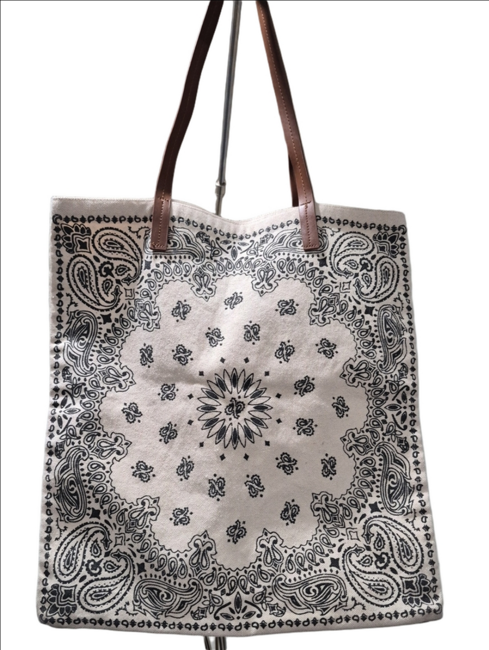 Beige canvas tote bag features a black paisley bandana pattern and brown straps
